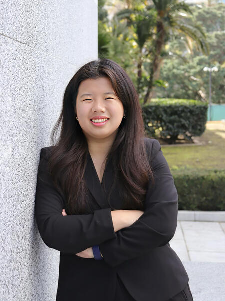 Candidate (Kylie) smiling for the camera while leaning right side of body on wall with arms crossed